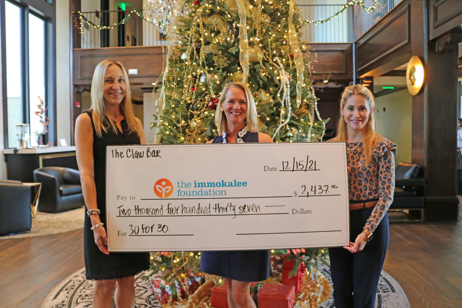 The Claw Bar’s Jeanne Tierney (left) and Megan Miller (center) present Marie Rubenstein (right), Director of Philanthropy at The Immokalee Foundation, a check for nearly $2,500 raised during the 30 for 30 Event.